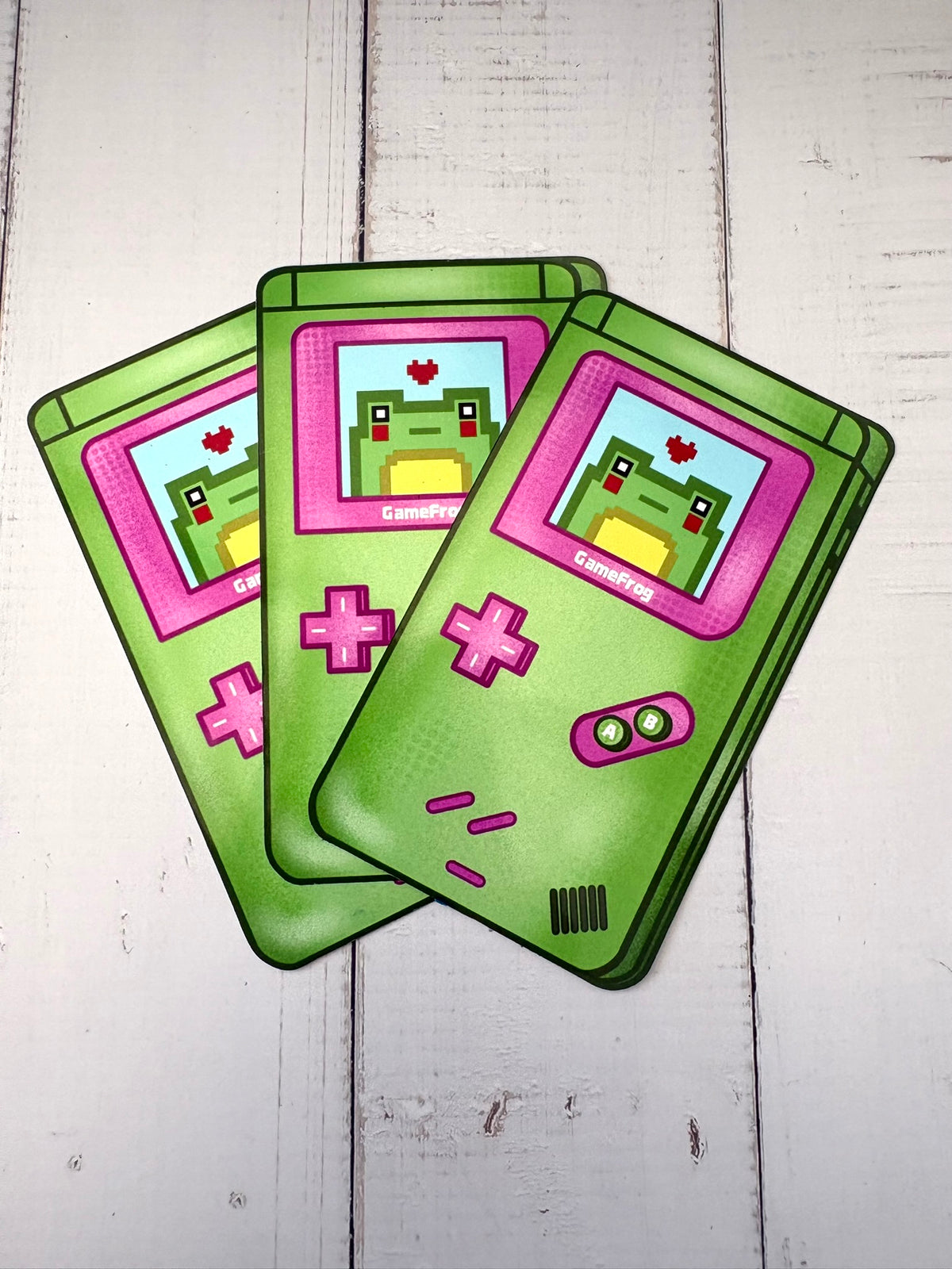 GameFrog Sticker - three stickers showing a retro green and pink handheld gaming console with pixel art frog on screen