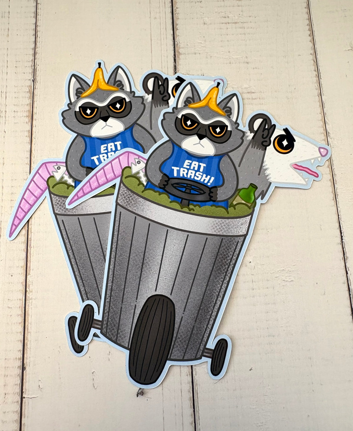 Raccoon and Possum Trash Trike Sticker - two stickers showing a raccoon in a crown riding a wheeled bin with a possum