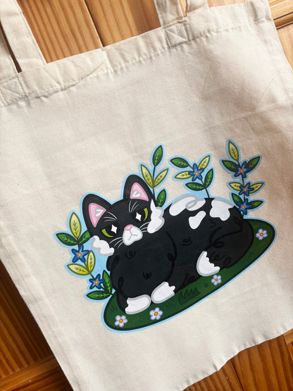 Close-up of the Garden Cat tote bag illustration with green leaves and blue flowers