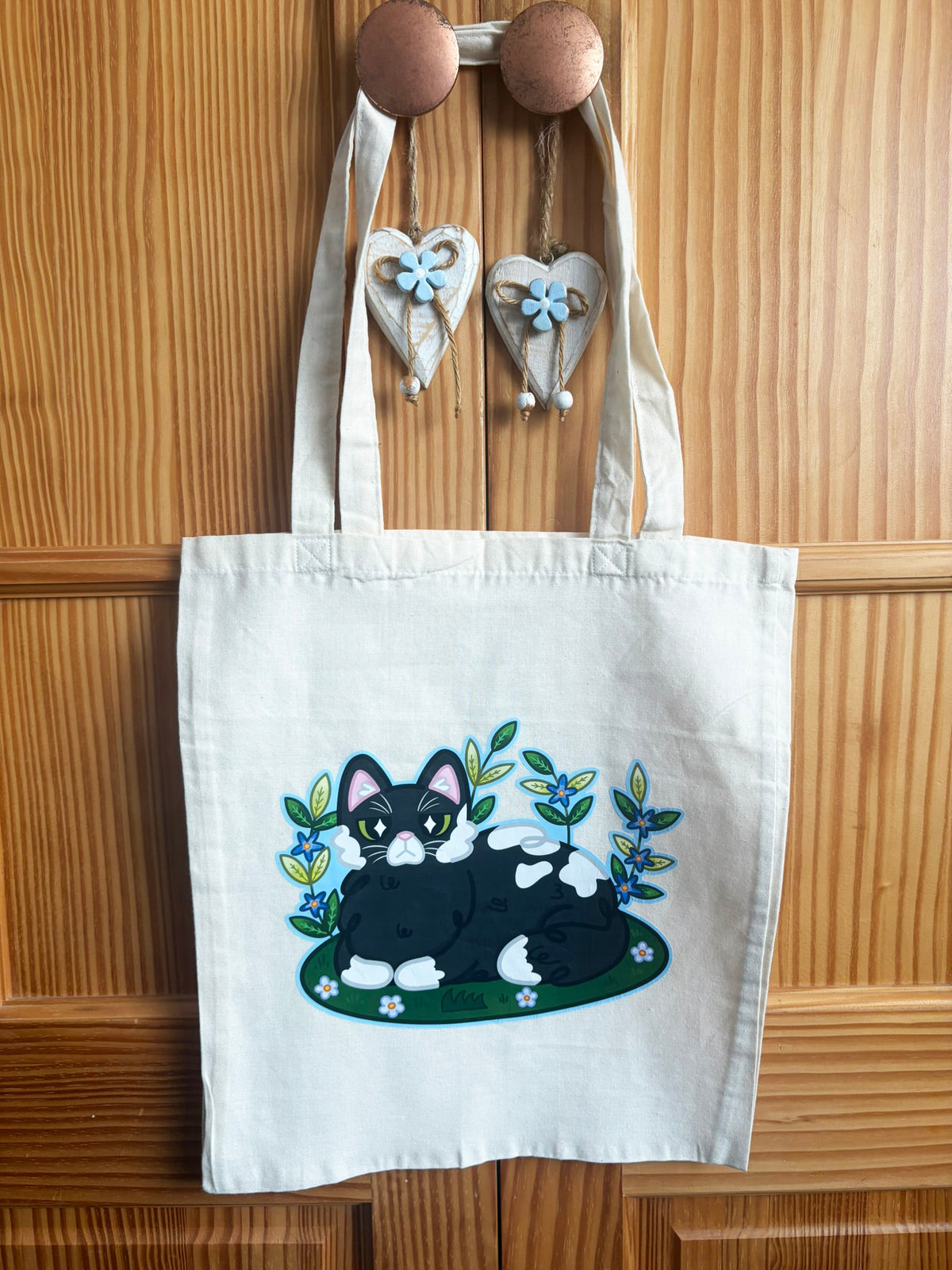 Cream Garden Cat tote bag with long handles and a black-and-white cat illustration among flowers